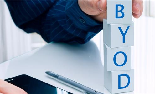 Businessman stacking blocks that spell "BYOD" on table